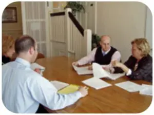 Four professionals sitting around a table in a meeting room, discussing documents.