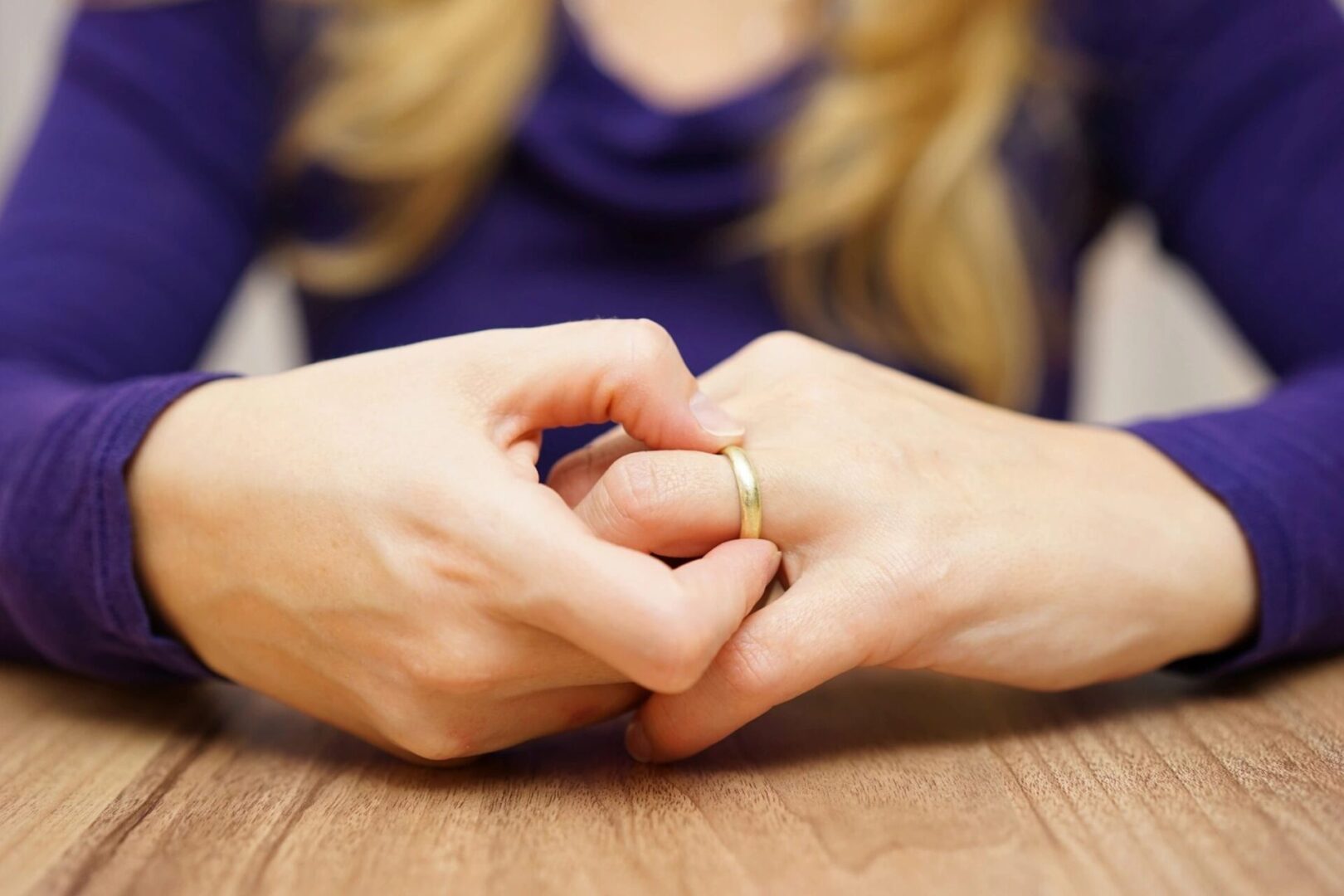 A woman is holding her hands together with a wedding ring.